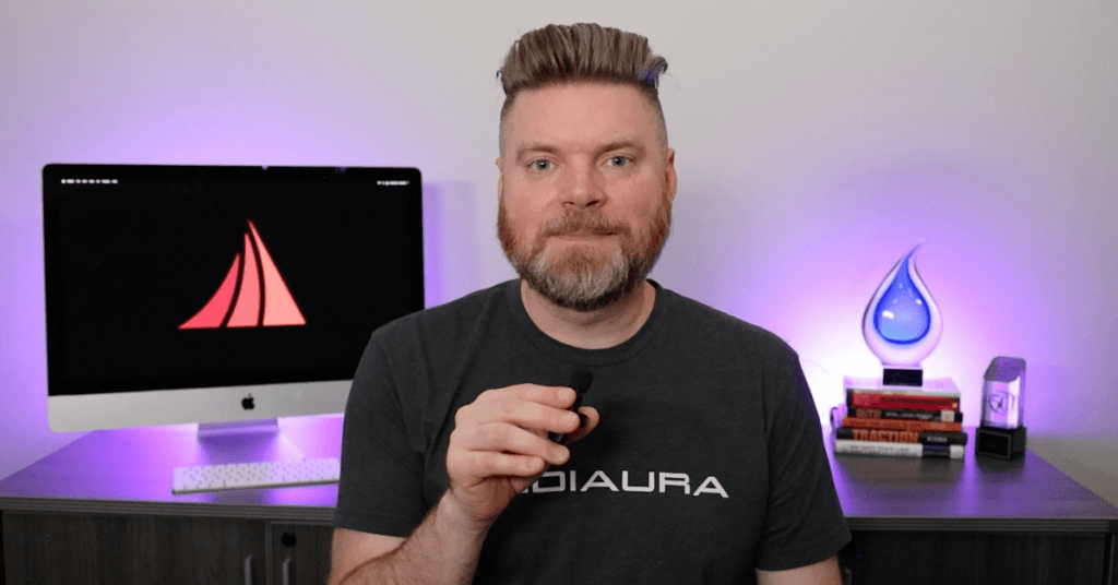 Andrew Aebersold, CEO of Mediaura, looks to camera as he explains seven mistakes you may make when building your own website. He sits in front of an office desk lir up by glowing purple lights.